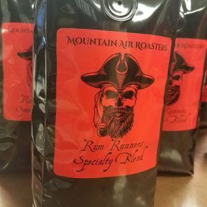 Mountain Air Roasters Rum Runners Specialty blend, black bag, big red sticker and a black pirate skull with pirate captains hat smoking an old cob pipe